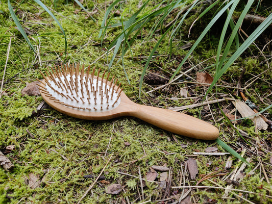 Stor hårbørste i bambus på gulv av mose